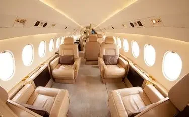 Spacious private jet cabin interior with cream leather seats arranged for comfortable business travel