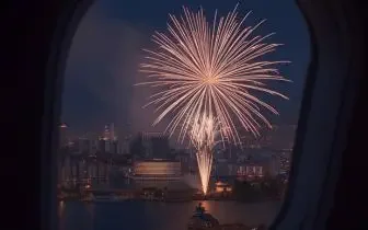 Spectacular fireworks display viewed through private jet window over illuminated cityscape during festive celebration