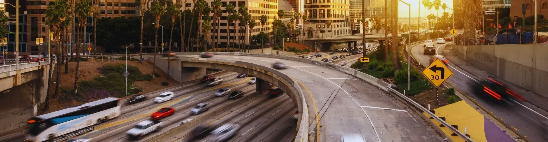 Downtown Los Angeles skyline at sunset with busy freeway traffic and palm trees for Van Nuys jet charter