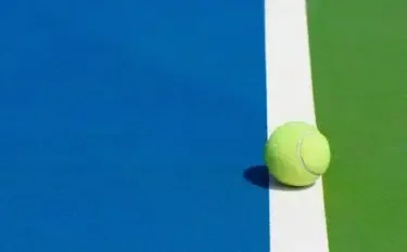 Tennis ball positioned on court lines with blue and green surfaces for US Open 2025 tournament coverage