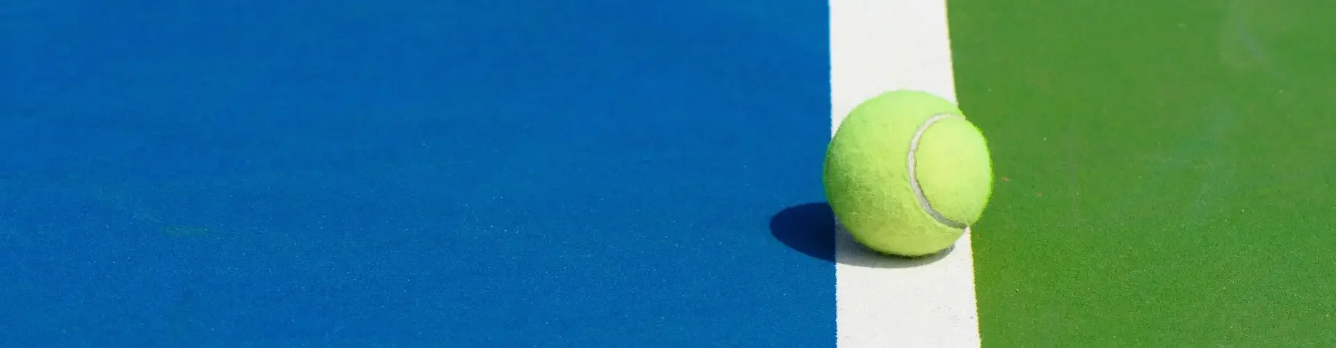 Tennis ball positioned on court lines with blue and green surfaces for US Open 2025 tournament coverage
