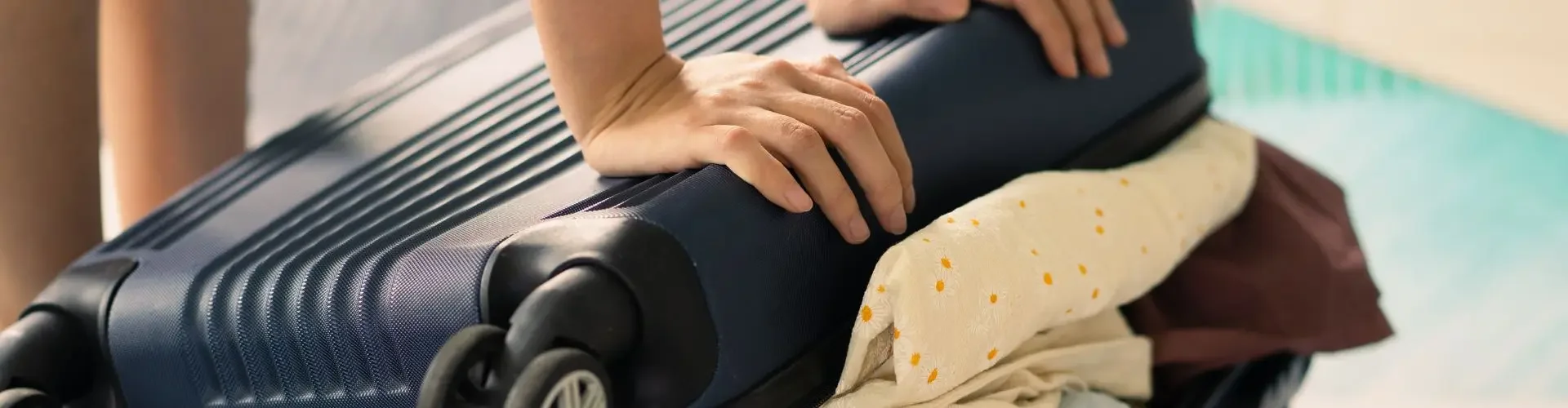 Hands packing luxury clothing into black suitcase for private jet travel with flexible baggage policies
