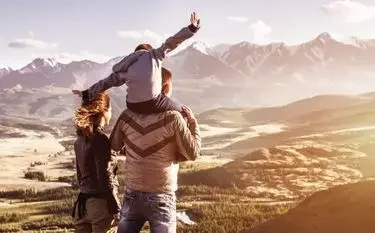 Two travelers celebrating with raised arms overlooking mountain valley, representing shared luxury travel experiences