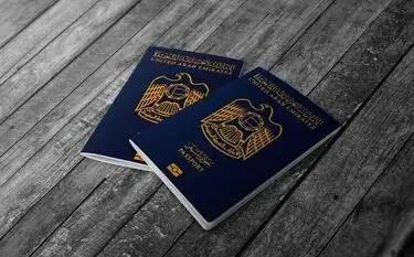Two UAE passports with golden emblems displayed on weathered wooden surface for international travel