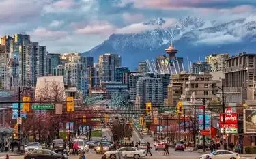 Vancouver downtown skyline with snow-capped mountains backdrop showcasing departure city for New York flights