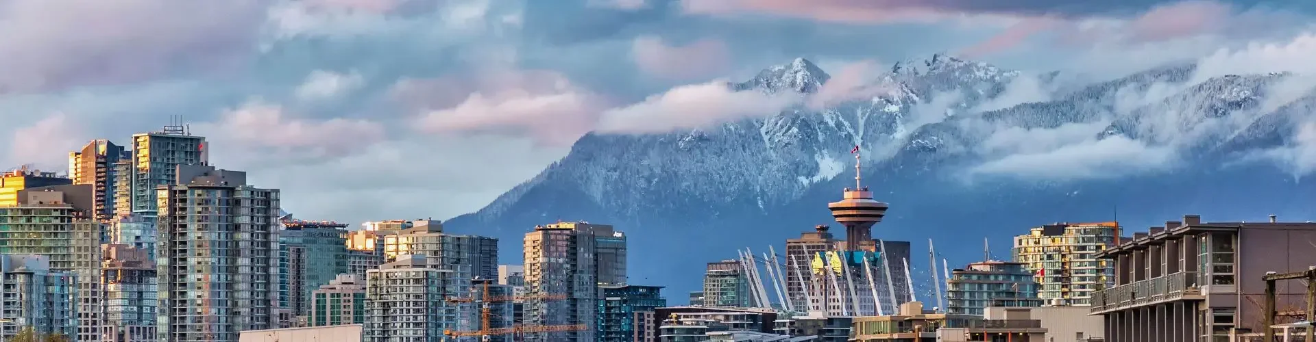 Vancouver downtown skyline with snow-capped mountains backdrop showcasing departure city for New York flights
