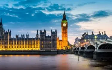Westminster Bridge and Big Ben illuminated at dusk reflecting in Thames River for UK private jet charter