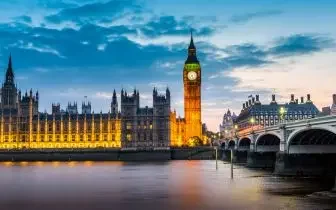 Westminster Bridge and Big Ben illuminated at dusk over Thames River in London for UK private jet travel