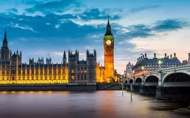 How Much Does It Cost to Charter a Private Jet in the UK? Westminster Palace and Big Ben illuminated at dusk beside Thames River for UK private jet travel guide