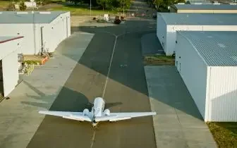 White air ambulance aircraft positioned on airport tarmac between hangars, ready for emergency medical transport