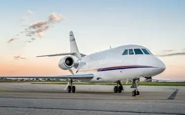 White luxury private jet parked on tarmac during golden hour sunset, showcasing premium charter aircraft