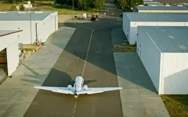 White medical aircraft positioned on airport tarmac between hangars ready for emergency transport flight