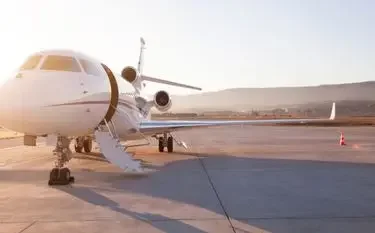 White private jet parked on airport tarmac at sunset with mountains in background for luxury travel