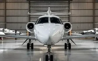White private jet parked in modern aircraft hangar, showcasing luxury charter options for Canadian routes
