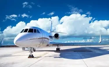 Are Private Jets Faster Than Commercial Planes? White private jet parked on tarmac under dramatic blue sky with puffy white clouds