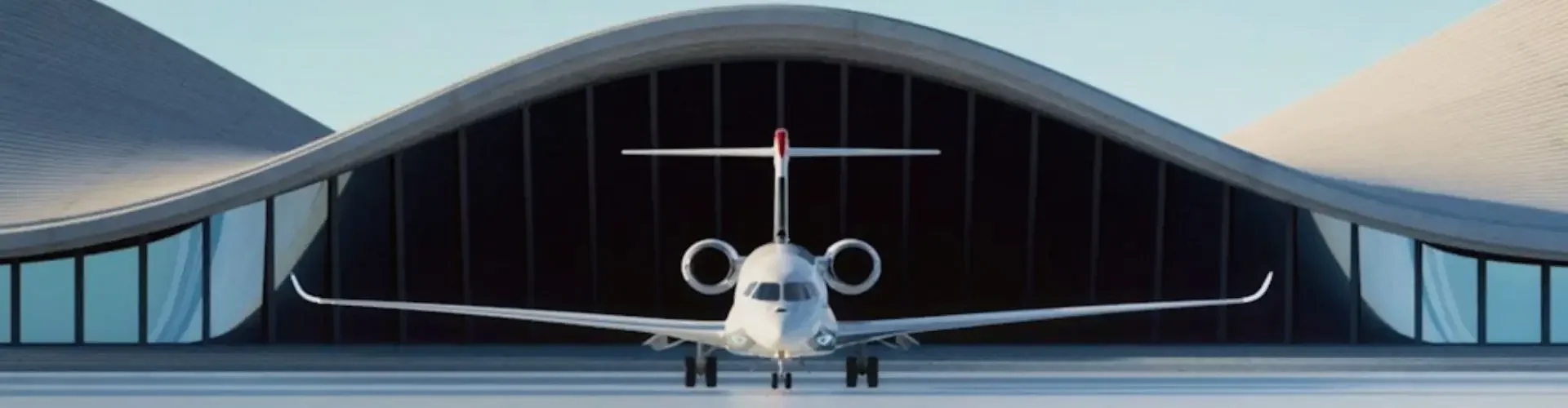 Is Flying Private Really Worth It in the US? Modern private jet positioned inside sleek curved hangar with glass walls under clear blue sky