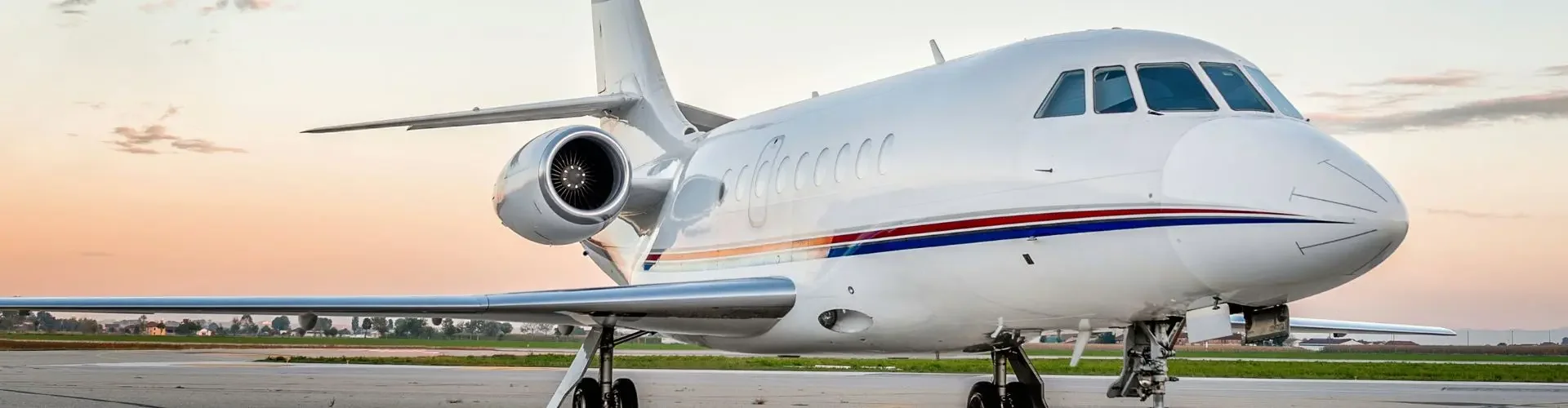 White luxury private jet parked on tarmac during golden hour sunset, showcasing premium charter aircraft