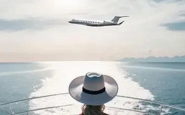 Woman in wide-brimmed hat watches luxury private jet fly over sparkling ocean from yacht deck