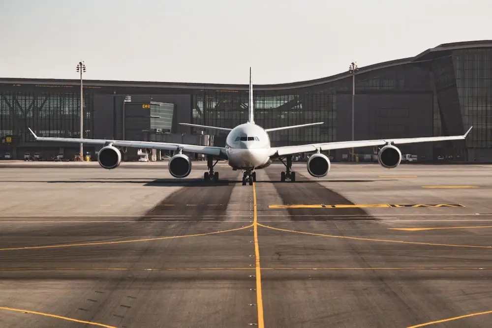 Commercial aircraft positioned on airport tarmac with modern terminal, illustrating empty leg flight opportunities