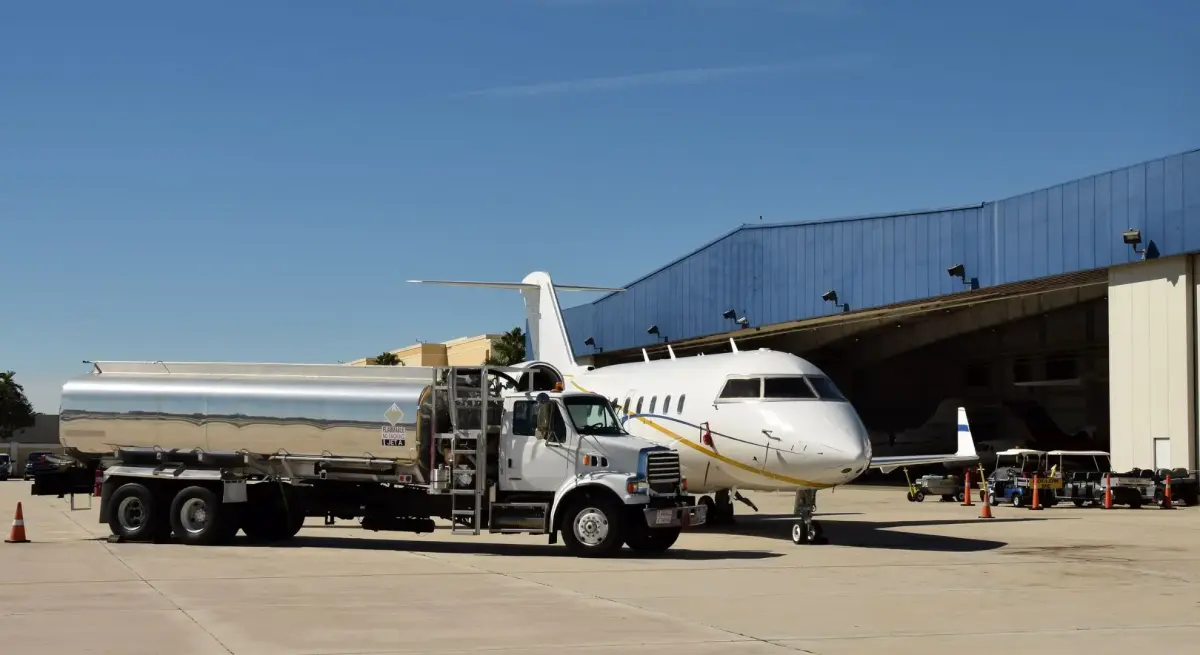 Fuel truck refueling white private jet at airport hangar demonstrating sustainable aviation fuel operations
