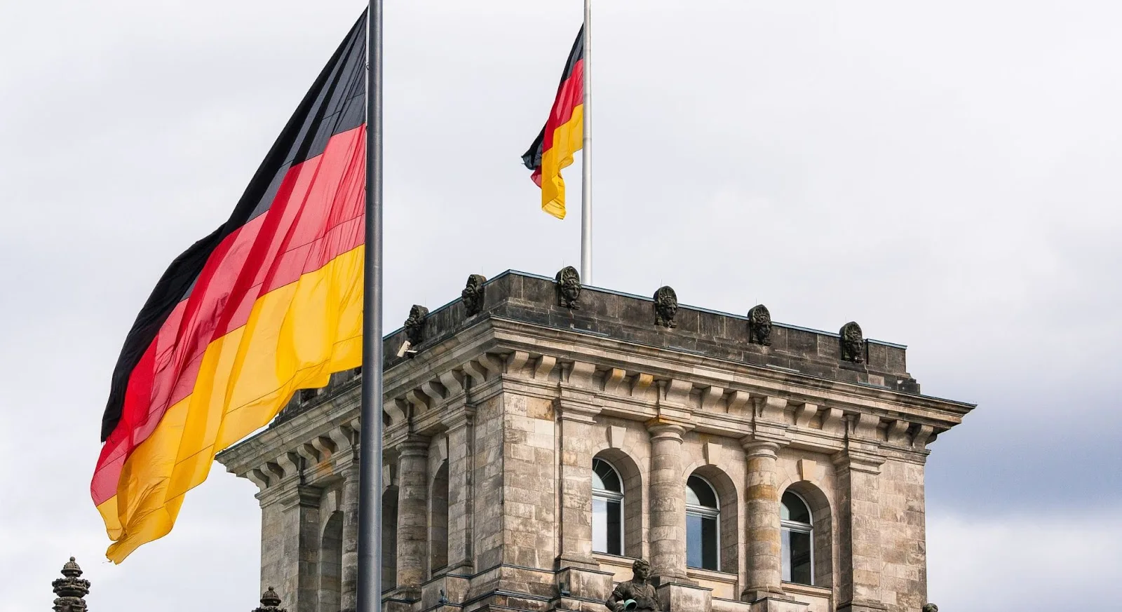 German flags flying beside historic Reichstag building in Berlin, showcasing luxury travel destination