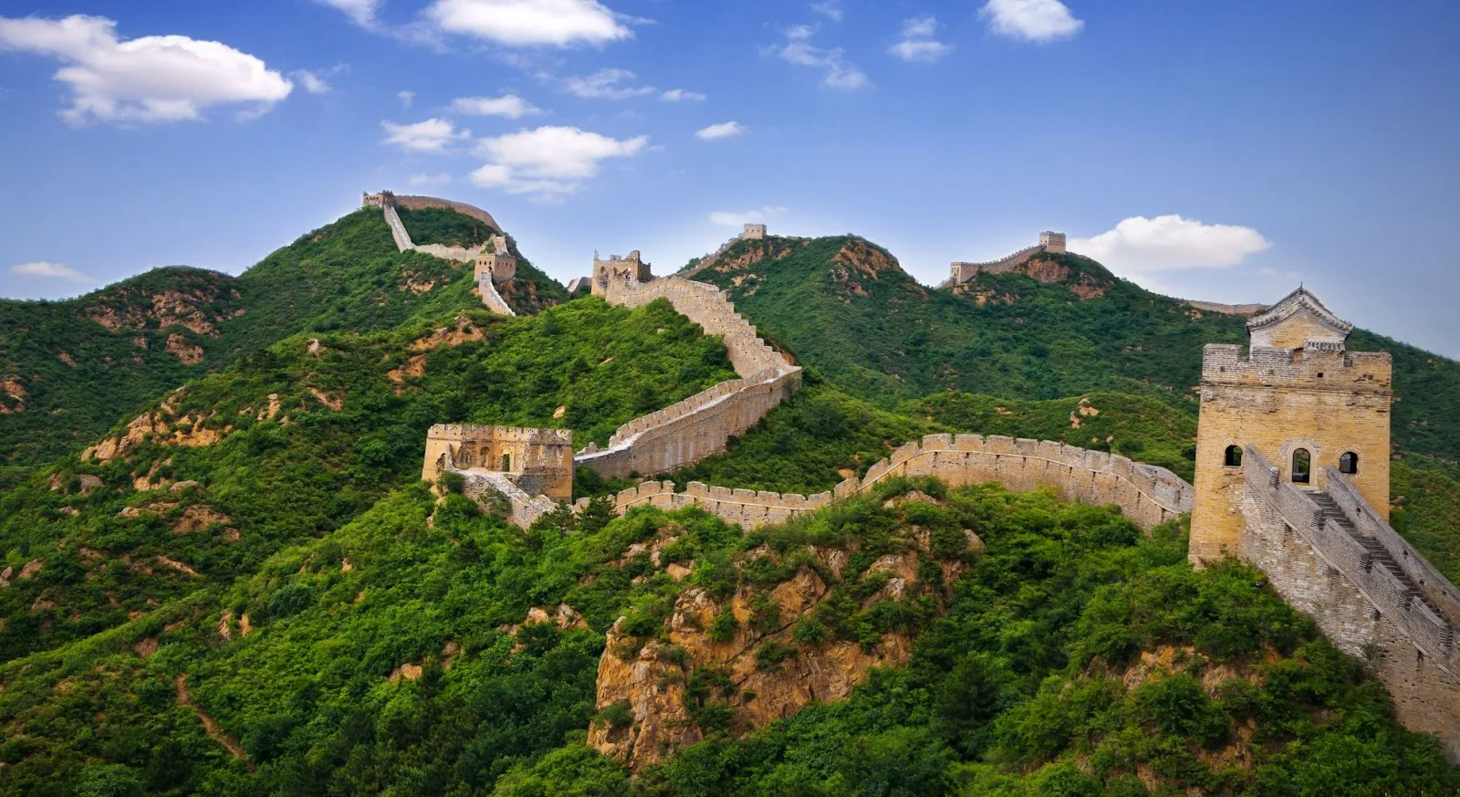 Great Wall of China winding through lush green mountains, showcasing Beijing's iconic landmark for luxury travelers