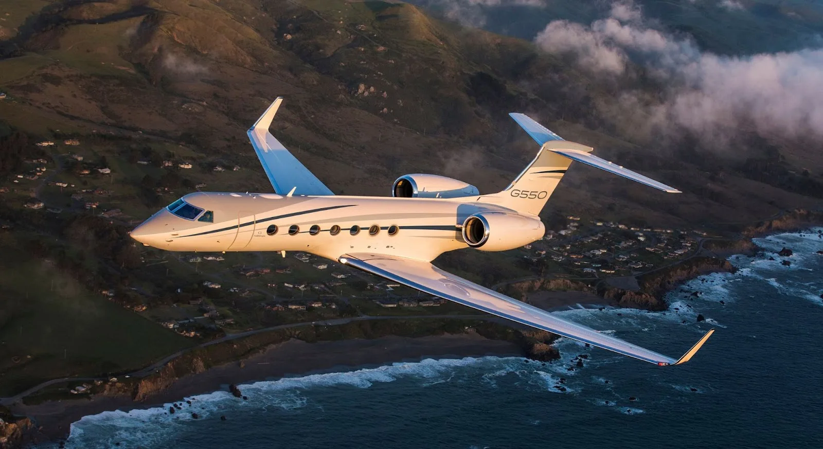 Gulfstream G550 private jet flying over dramatic coastal landscape showcasing luxury empty leg charter opportunities