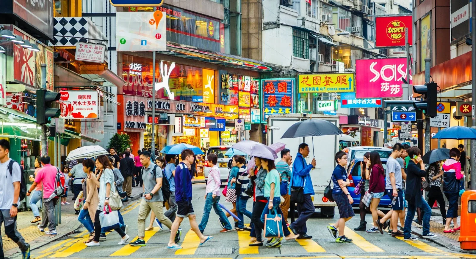 Bustling Hong Kong street crossing with pedestrians and colorful neon signs showcasing vibrant city life
