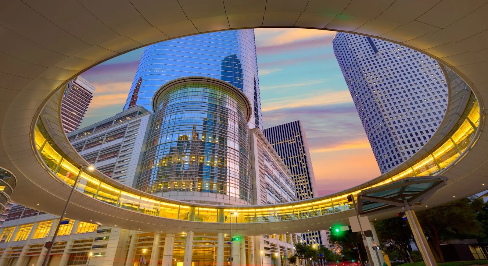 Modern downtown Houston skyline viewed through illuminated circular walkway at dusk showcasing luxury travel destination
