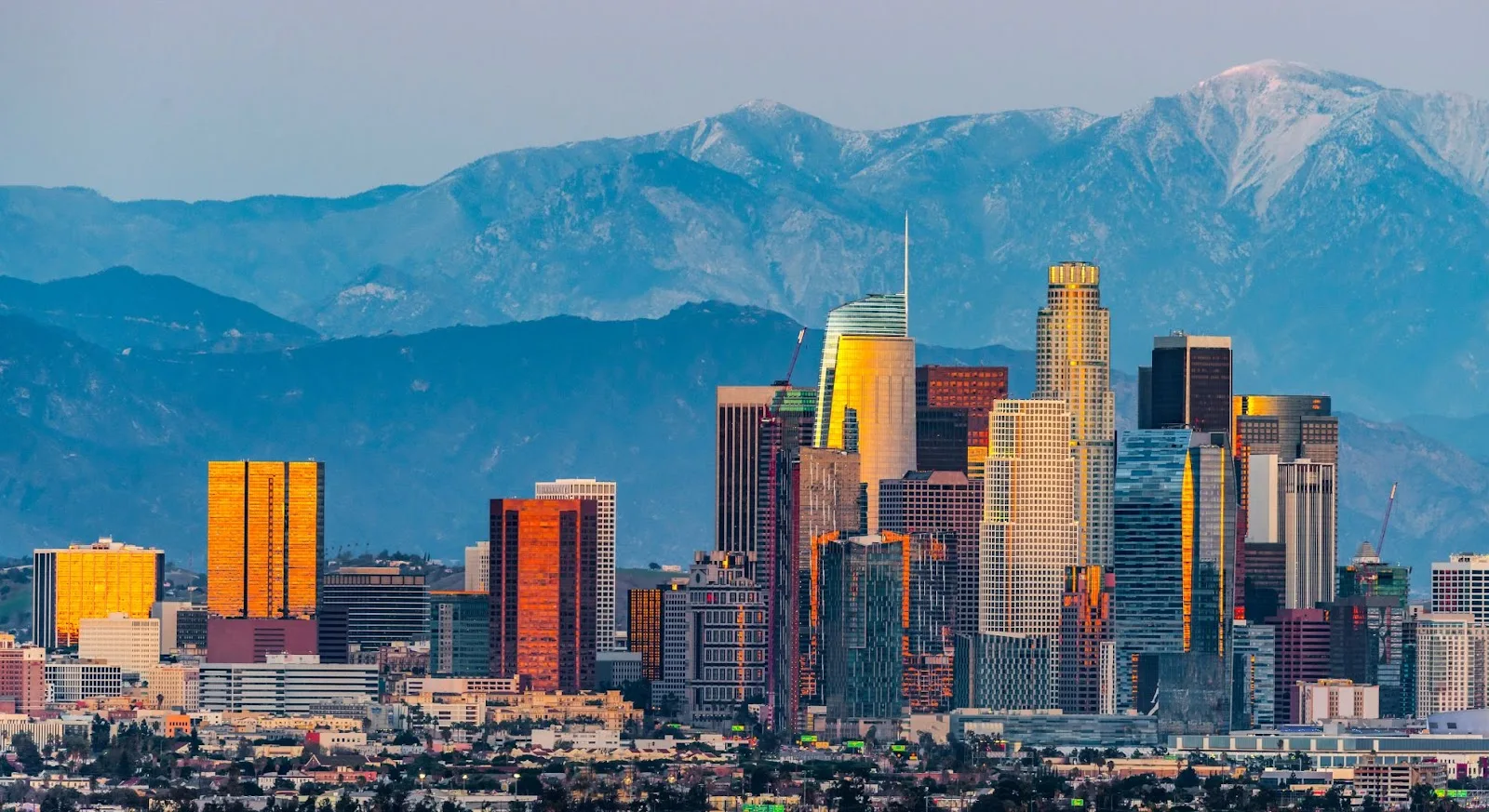 Downtown Los Angeles skyline with snow-capped mountains backdrop showcasing premium destination for luxury jet travel