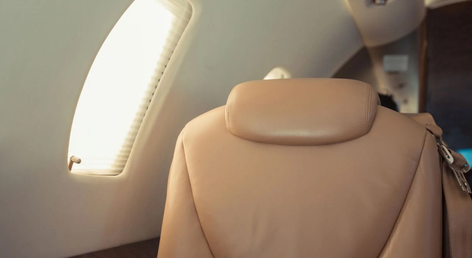 Luxurious beige leather seats beside aircraft window showcasing premium cabin comfort on empty leg flights