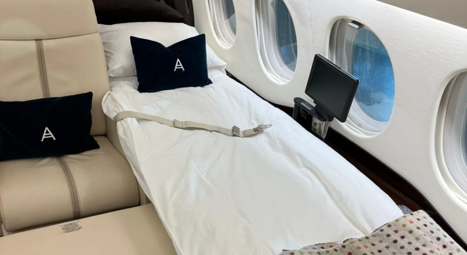 Luxurious private jet bedroom with crisp white bedding and entertainment system for long-haul flights