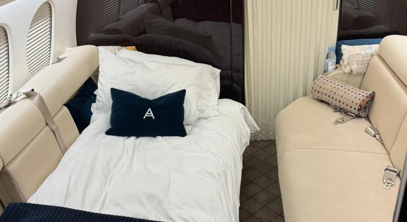 Luxurious private jet bedroom with crisp white bedding and navy pillow, showcasing premium comfort for long-haul flights