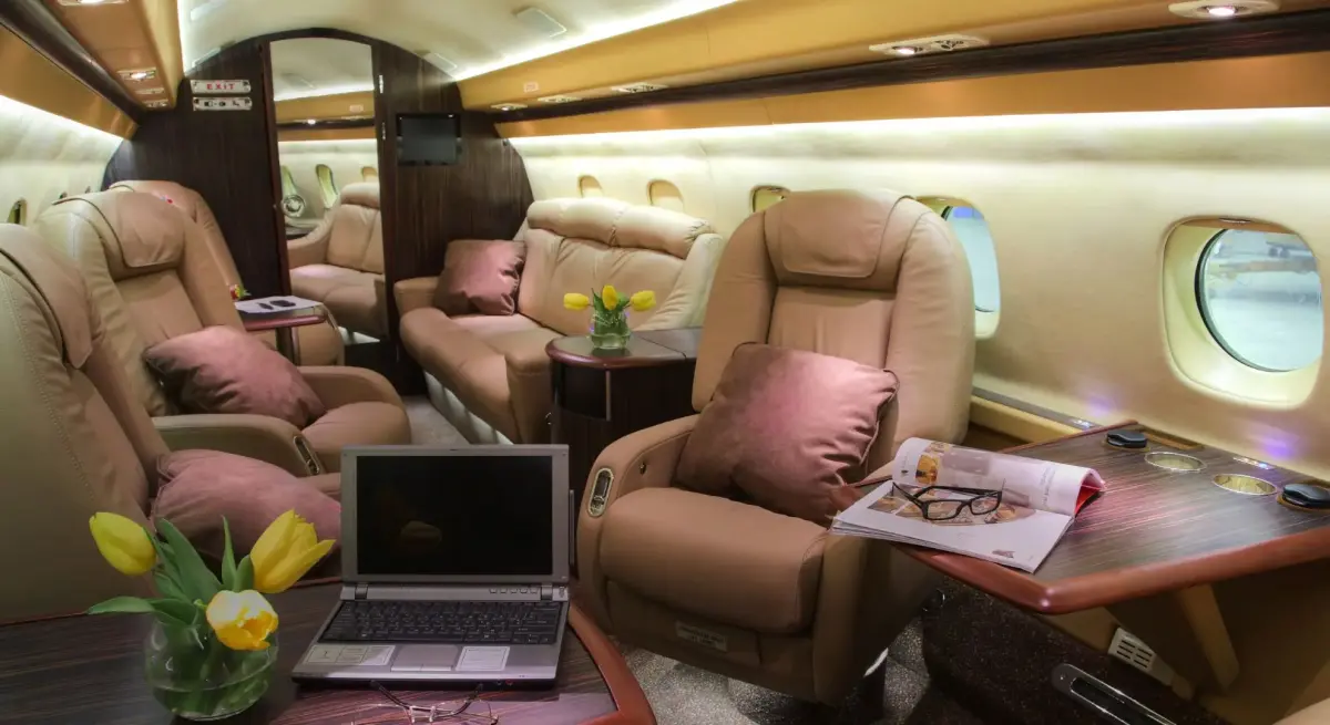Luxurious private jet cabin interior with leather seating and work tables for business travel compliance