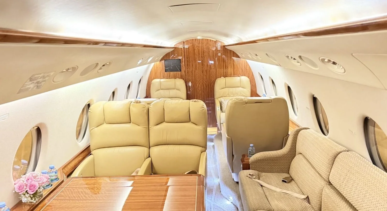 Luxurious private jet cabin interior with cream leather seating and wood accents for Singapore to Sydney route