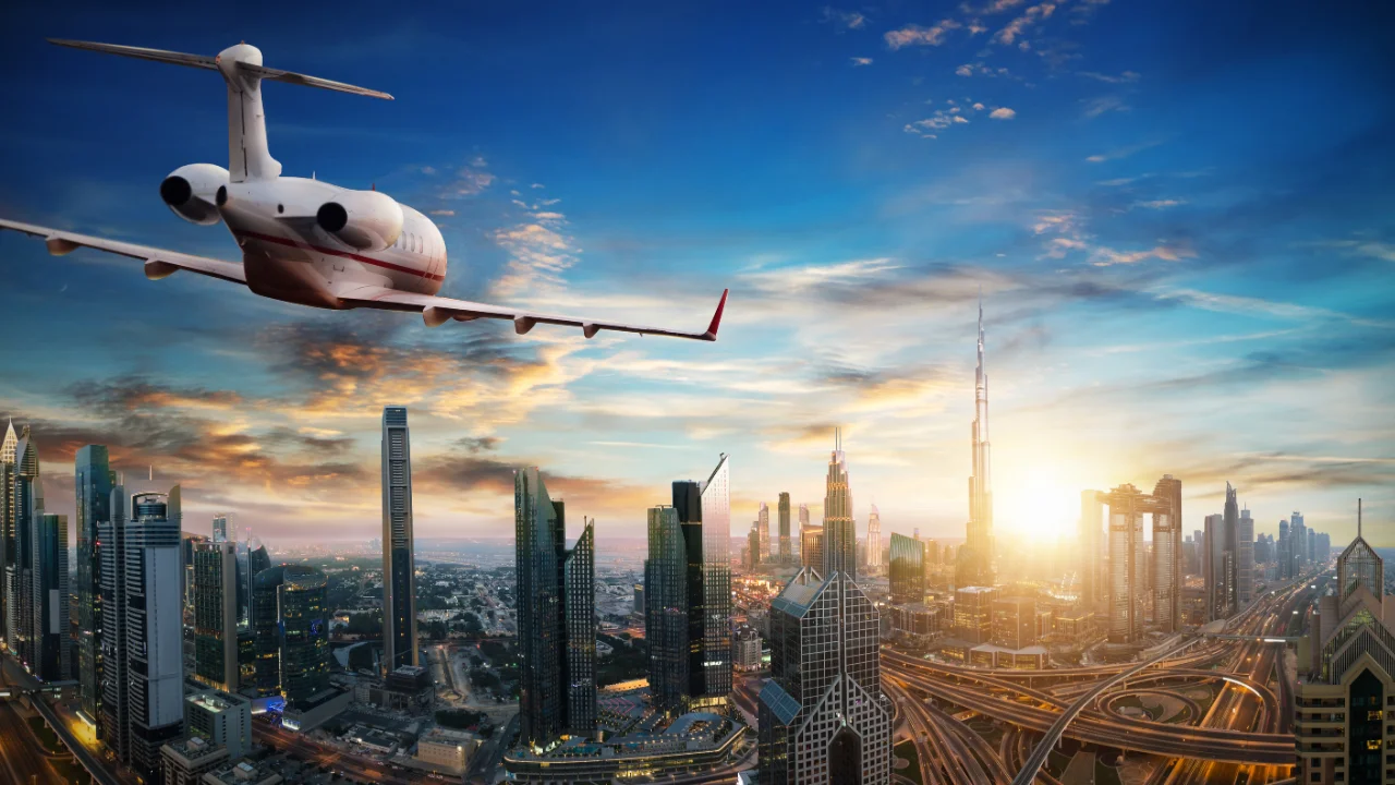 Luxury private jet soaring above Dubai's illuminated skyline at sunset, showcasing premium empty leg flight routes