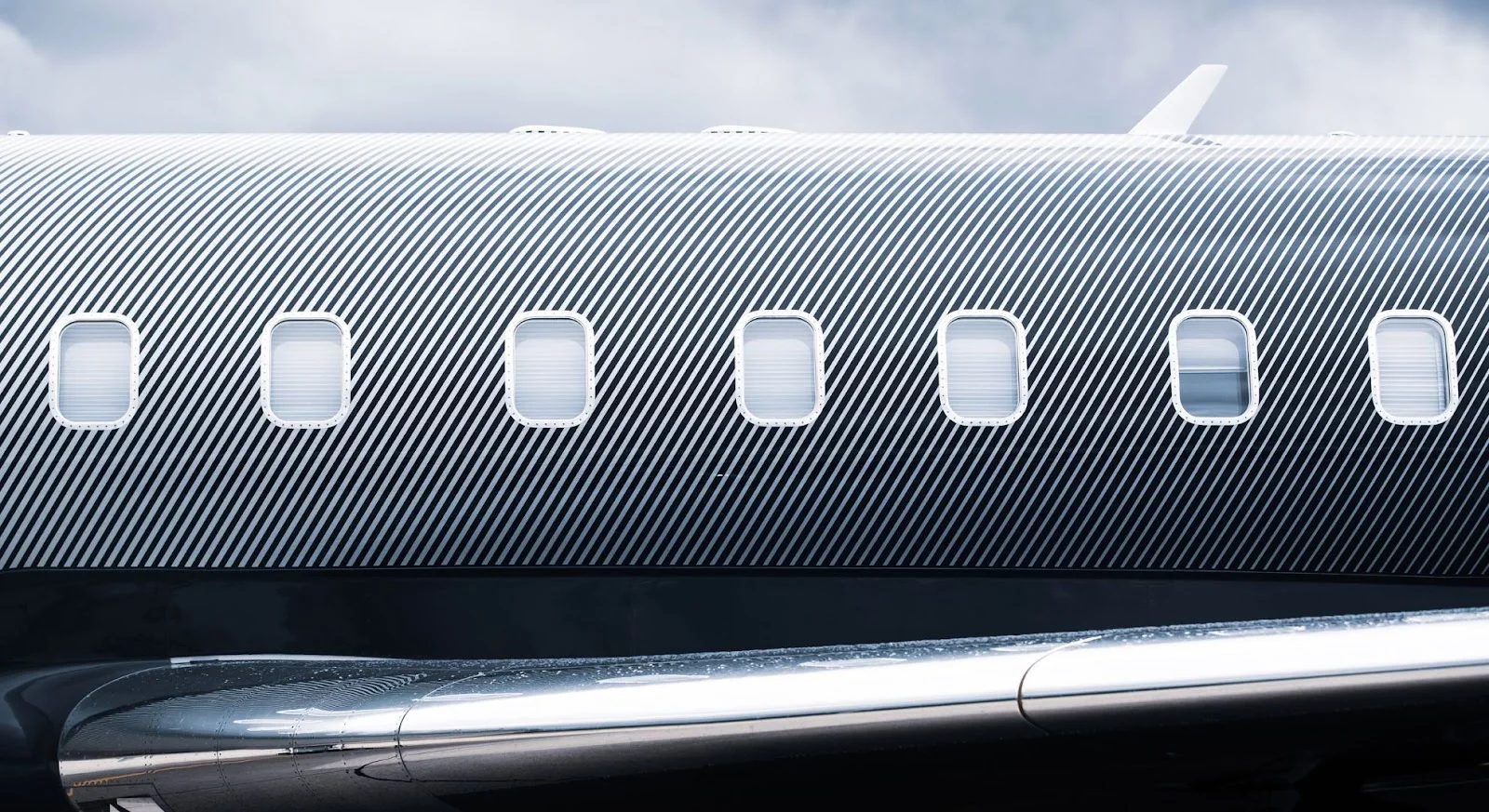 Close-up view of luxury private jet fuselage with passenger windows showcasing premium aircraft design