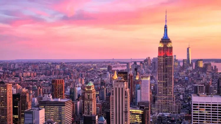 Manhattan skyline at sunset with Empire State Building illuminated, showcasing luxury travel destination