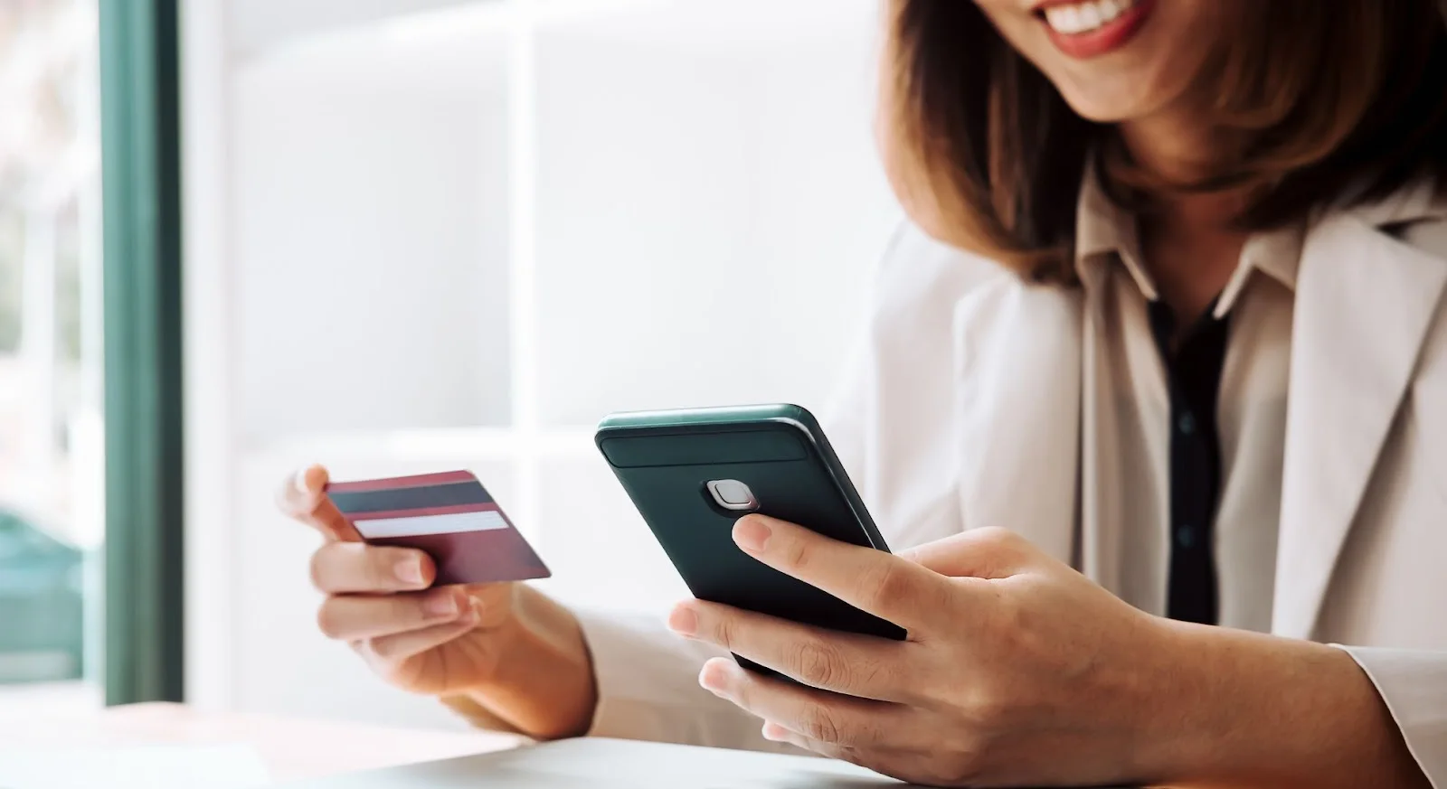 Professional woman using smartphone and credit card for secure online private jet booking payment