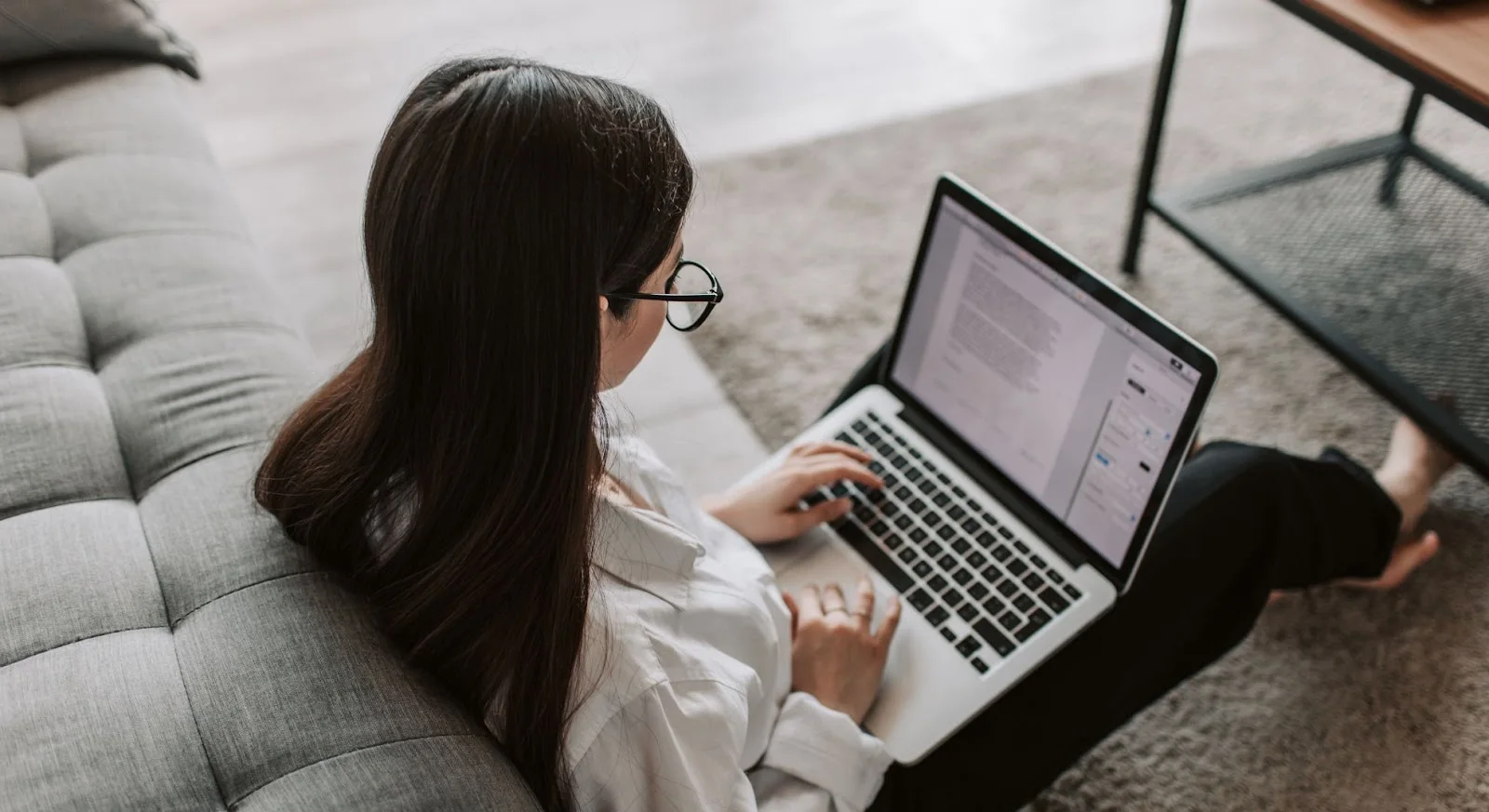 Professional woman researching empty leg flights on laptop while relaxing on modern sofa at home