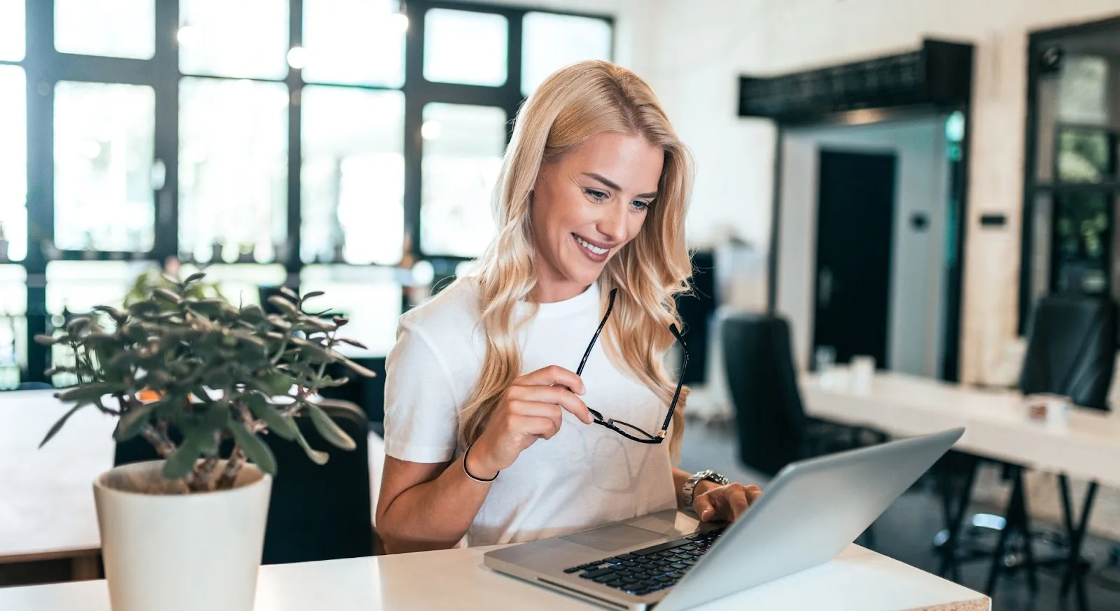 Professional woman researching empty leg flights on laptop in modern office setting