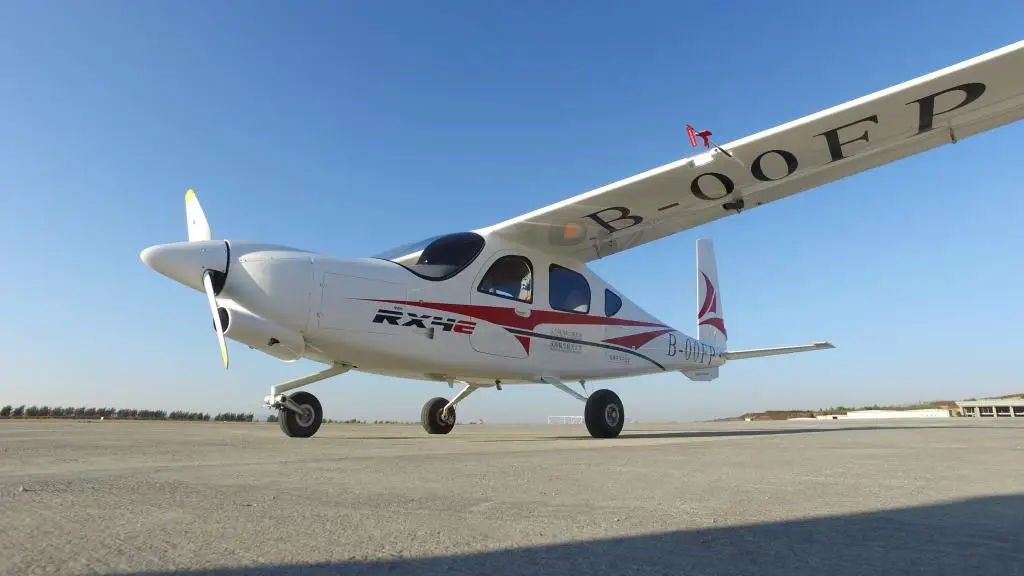White RX4E electric aircraft with red accents parked on airport tarmac under clear blue sky