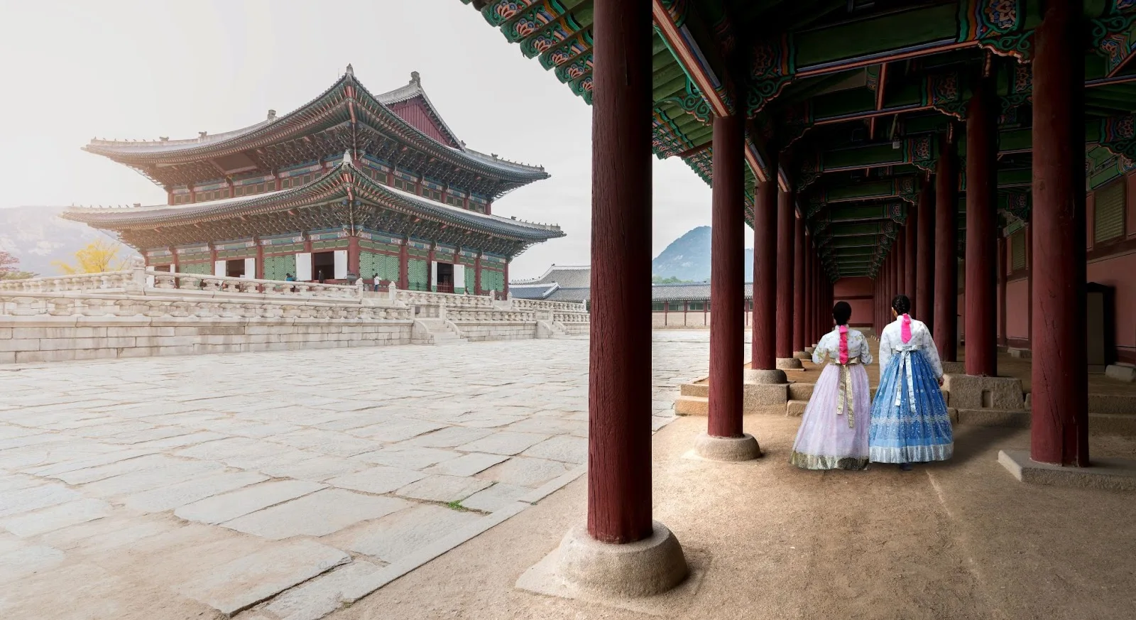 Two women in traditional Korean hanbok dresses exploring Gyeongbokgung Palace courtyard in Seoul