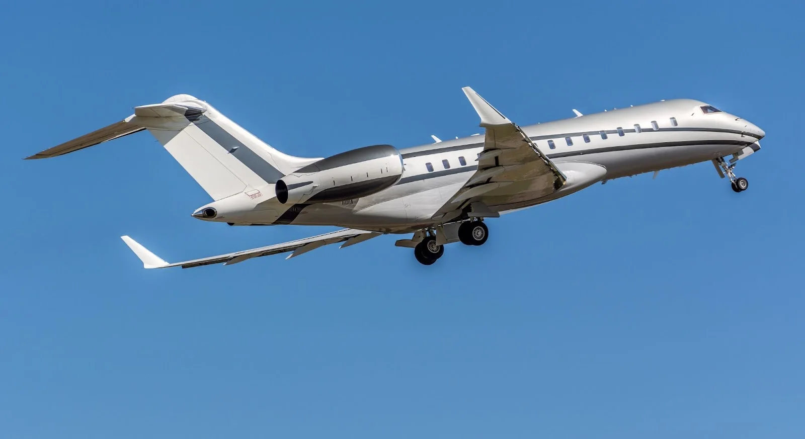 White luxury private jet flying against clear blue sky showcasing premium aircraft for empty leg charter flights