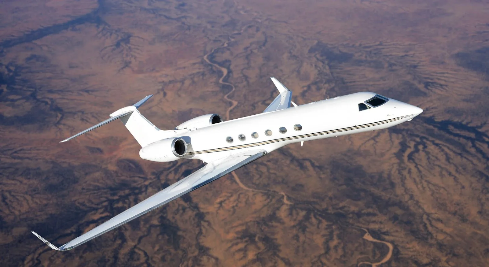 White private jet cruising above desert landscape showcasing luxury empty leg charter flight opportunities