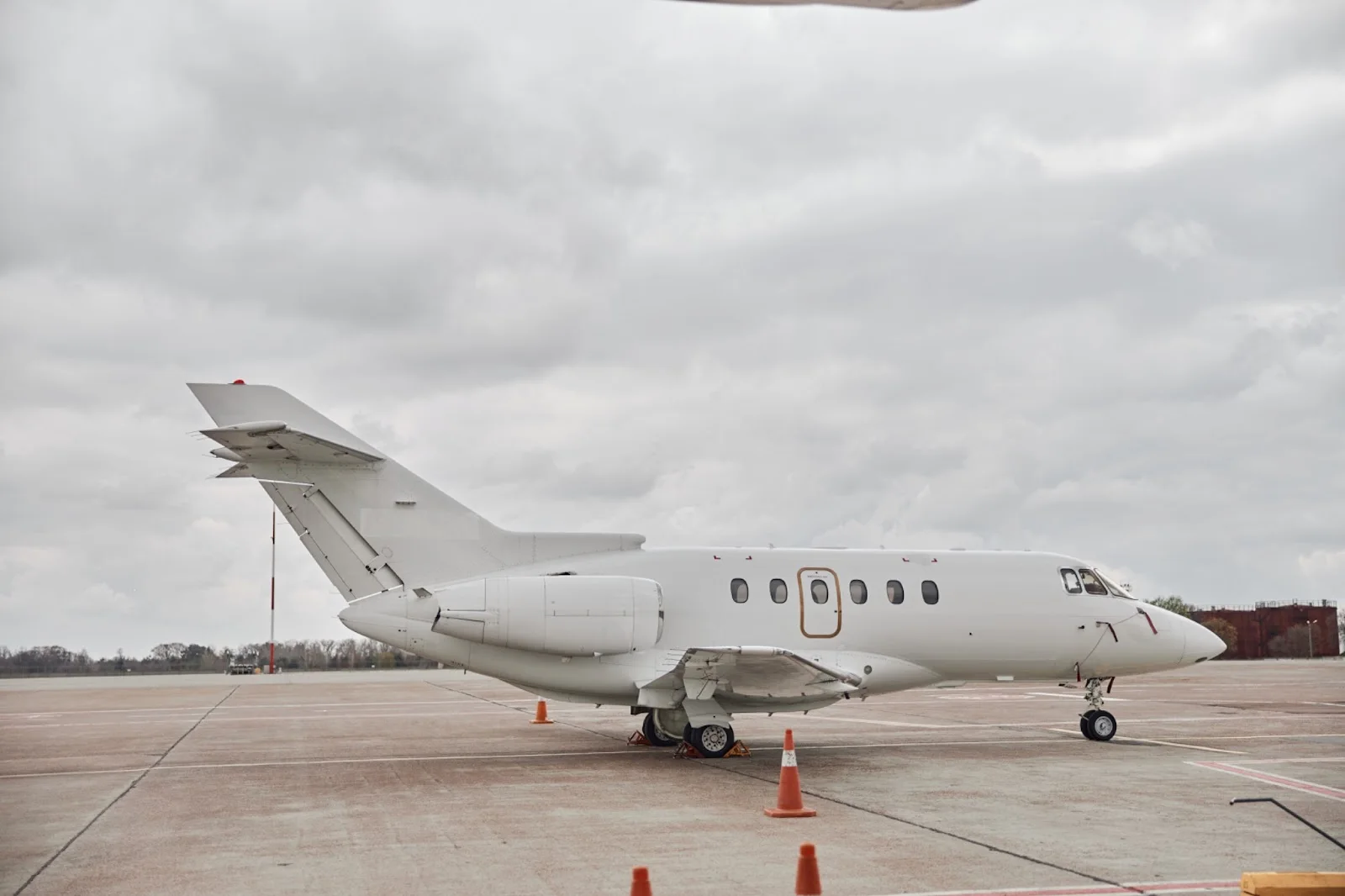White private jet parked on airport tarmac with safety cones, ready for empty leg charter flight