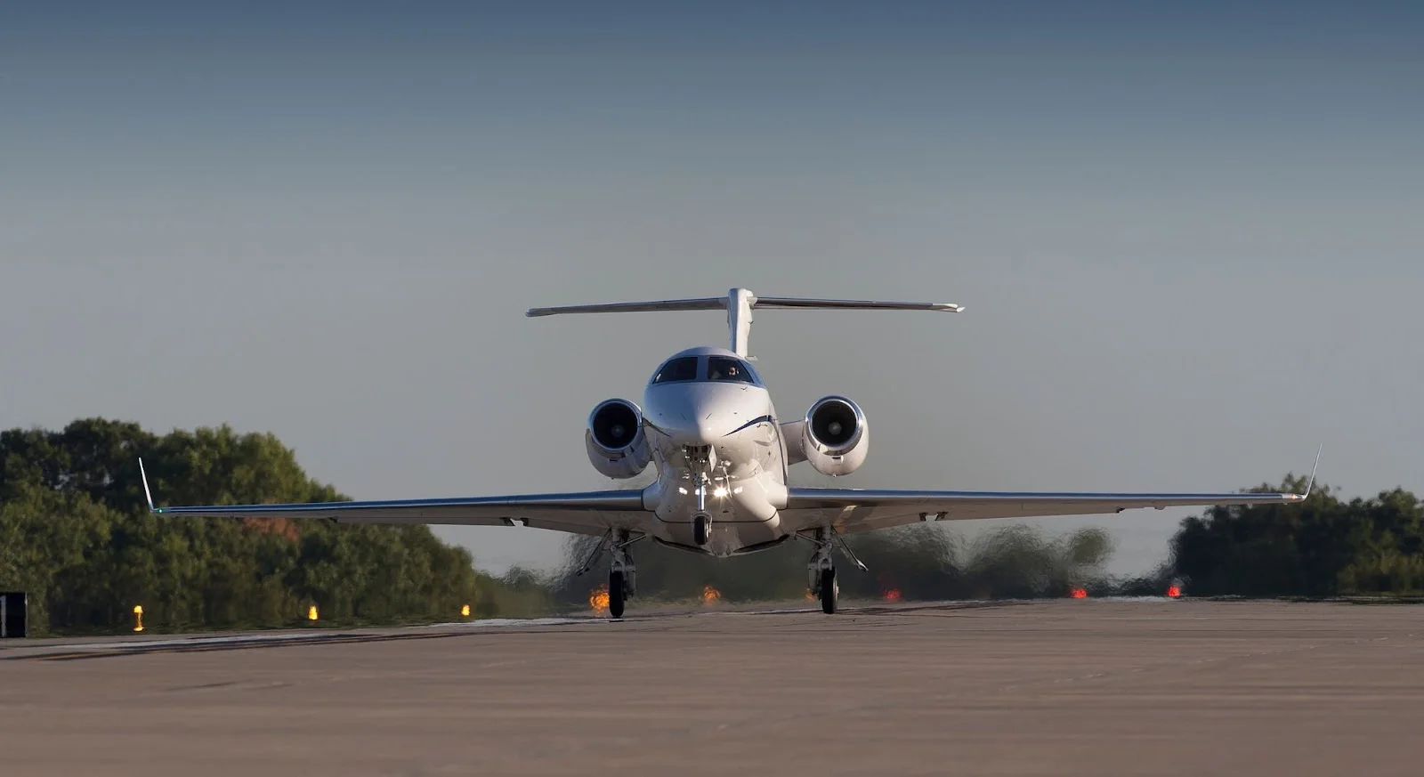 White private jet taxiing on runway at sunset, demonstrating luxury aircraft available for empty leg flights