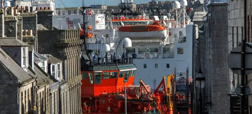 Aberdeen harbour with orange offshore supply vessels and granite buildings lining the street in Scotland