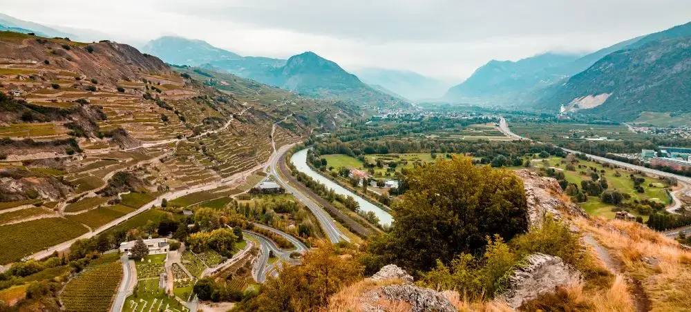 Aerial view of Sion, Switzerland, with the Rhône Valley, vineyards, and Alpine mountains as seen from Tourbillon Castle hill