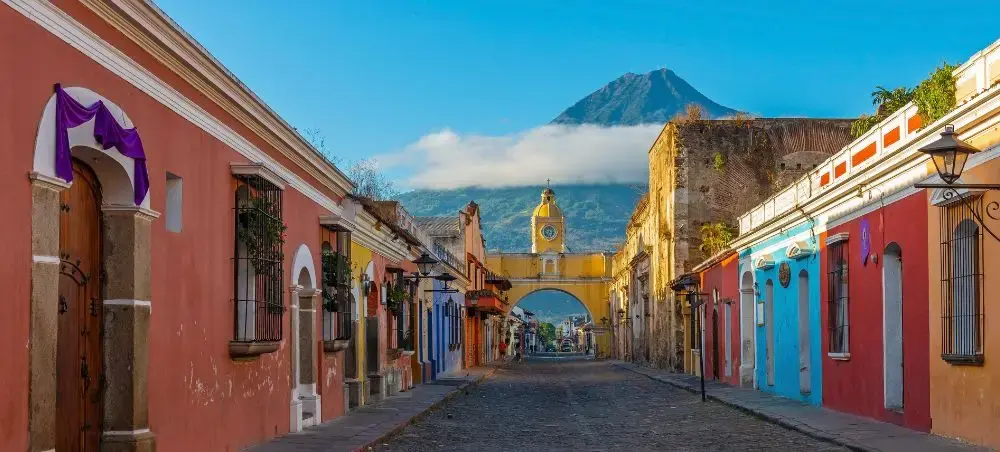 Cityscape of a street in Antigua with Santa Catalina Arch and Agua volcano in the background